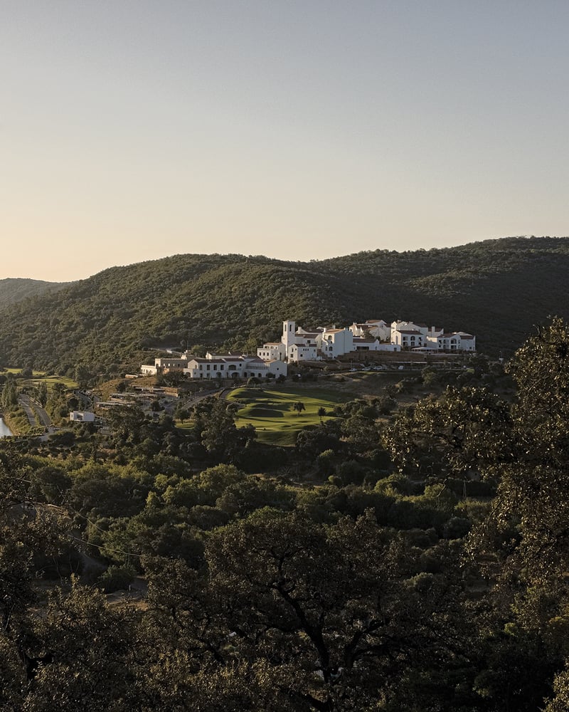 The whitewashed buildings of Portugal’s Viceroy at Ombria Algarve, surrounded by forested green hills.