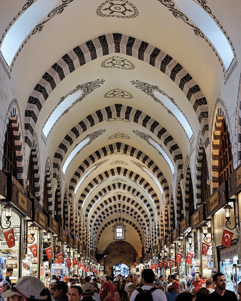 A throng of people visiting food stalls under an ornate ceiling in Istanbul’s bazaar.