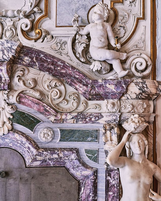 A detail of Orient Express Venezia’s library with carved marble, gilded scrollwork, and sculptural human figures.