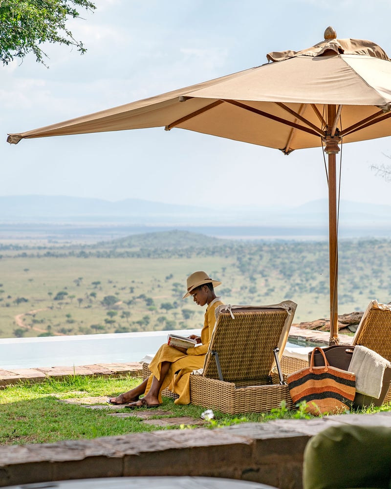 A woman reads a book at Singita Sasakwa in Tanzania.