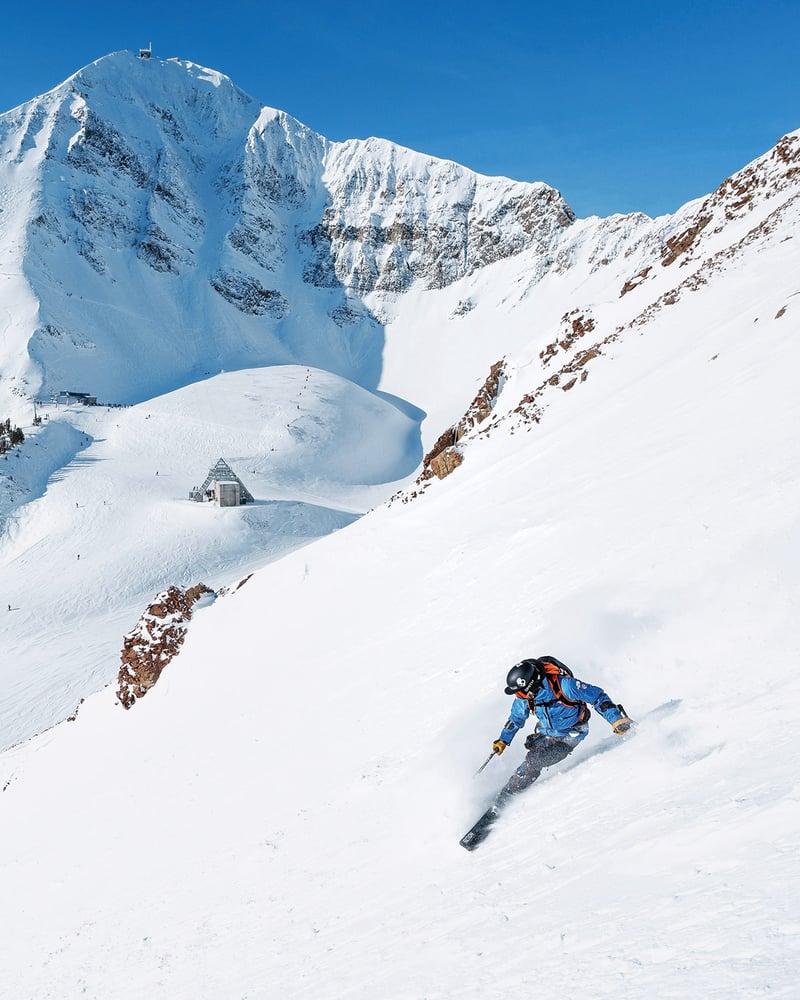 A skier tears down a snowy mountain in Big Sky, Montana.