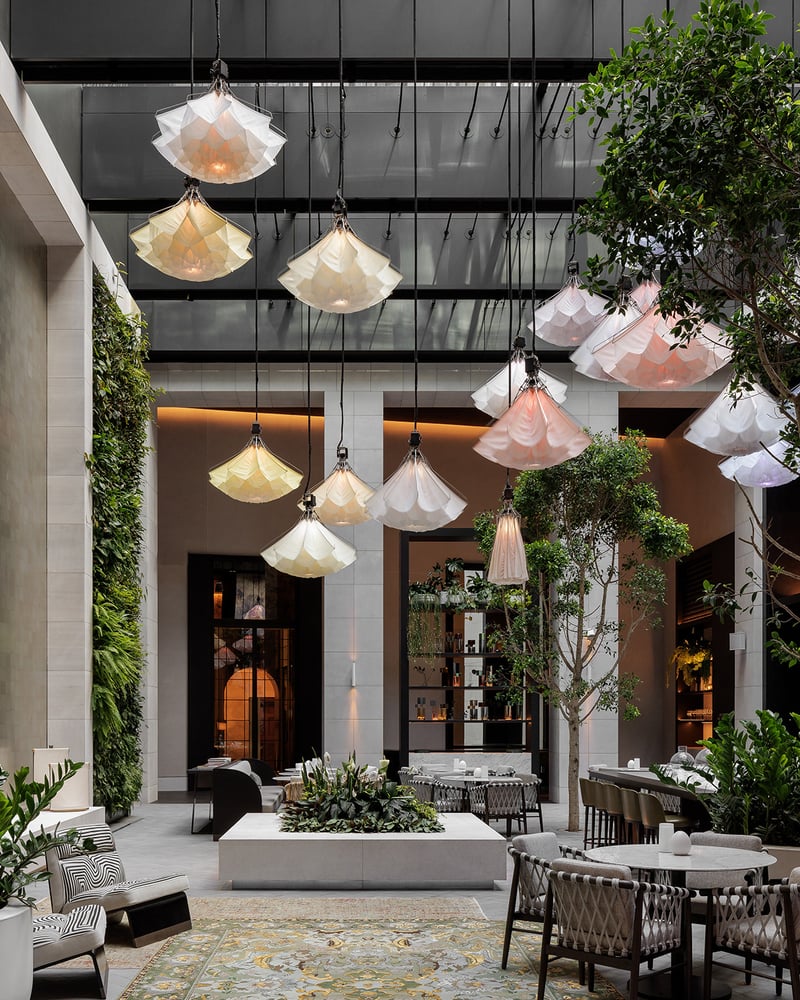 A flower art installation hangs from the ceiling in a greenhouse.