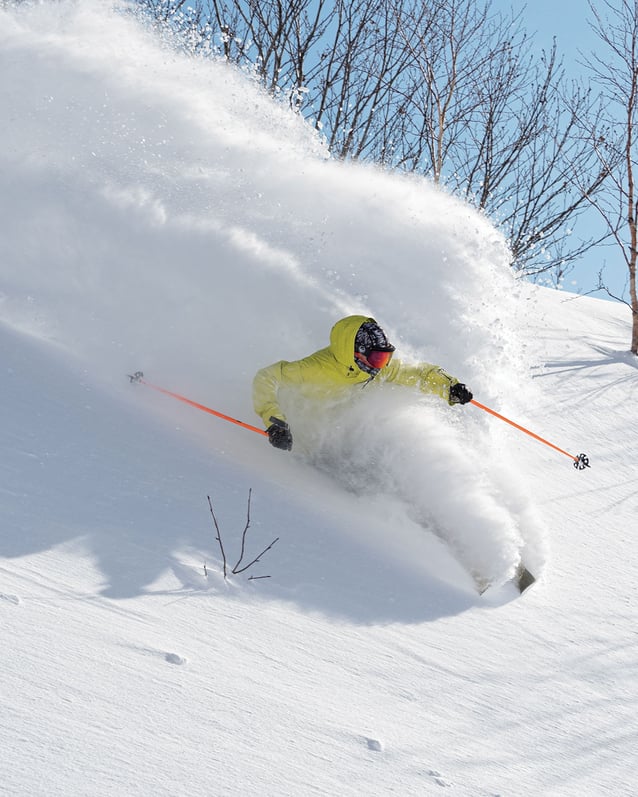A neon-yellow-clad skier heads down a powdery mountain in Niseko.