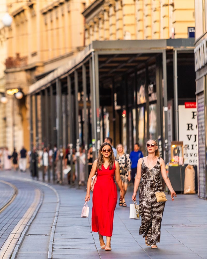 Two women carrying shopping bags stroll the promenade in Zagreb.