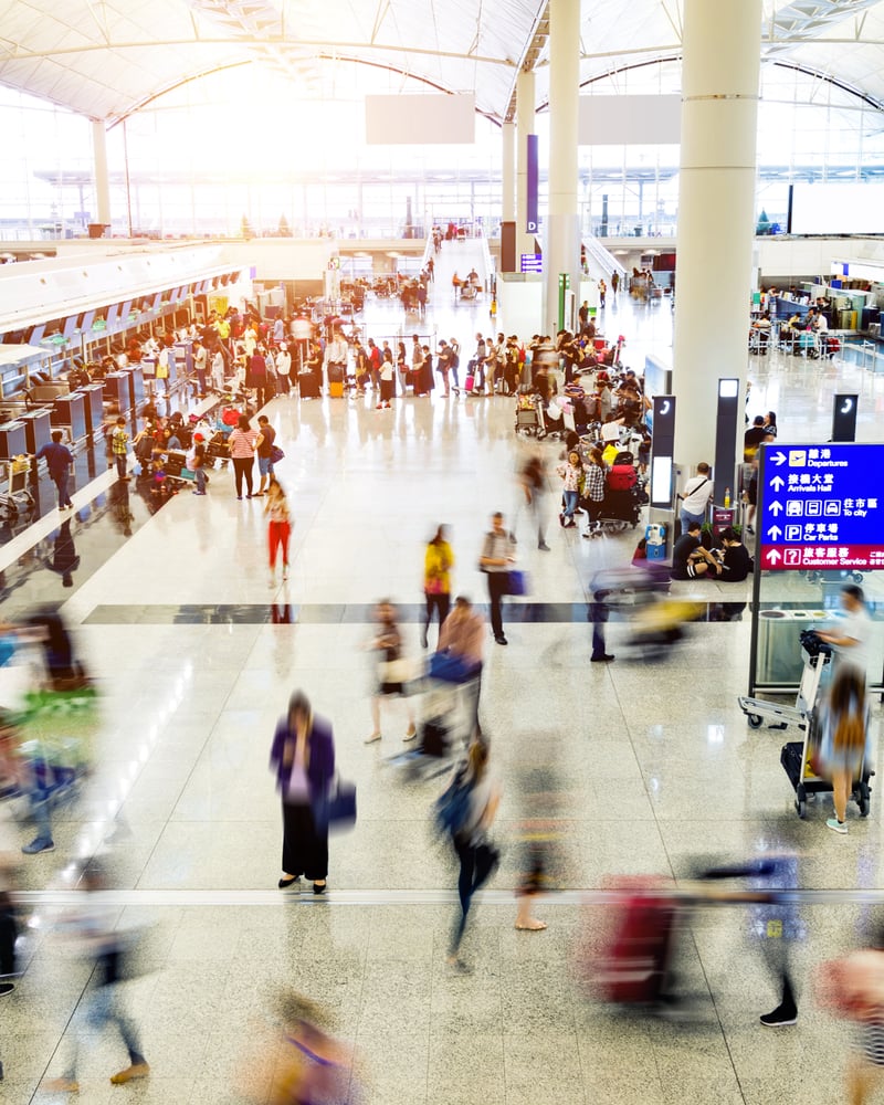 An overhead view of travelers moving through a busy airport.