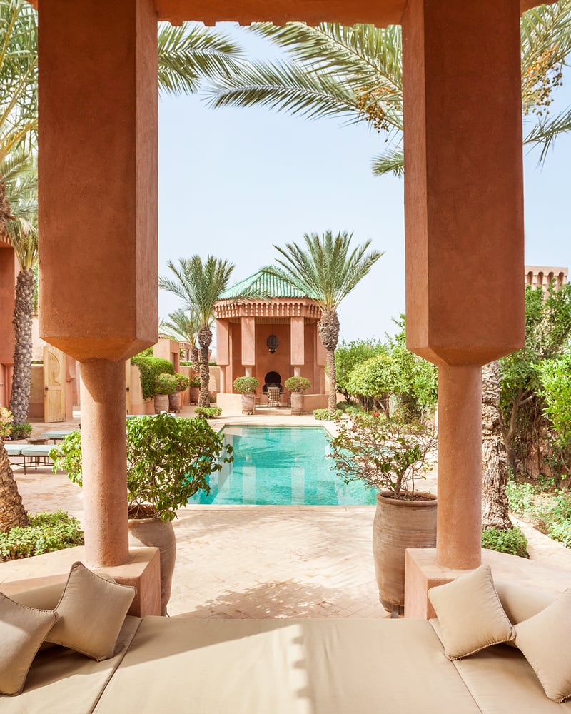 A seating area at Amanjena's Al Hamra Maison overlooks a pool.