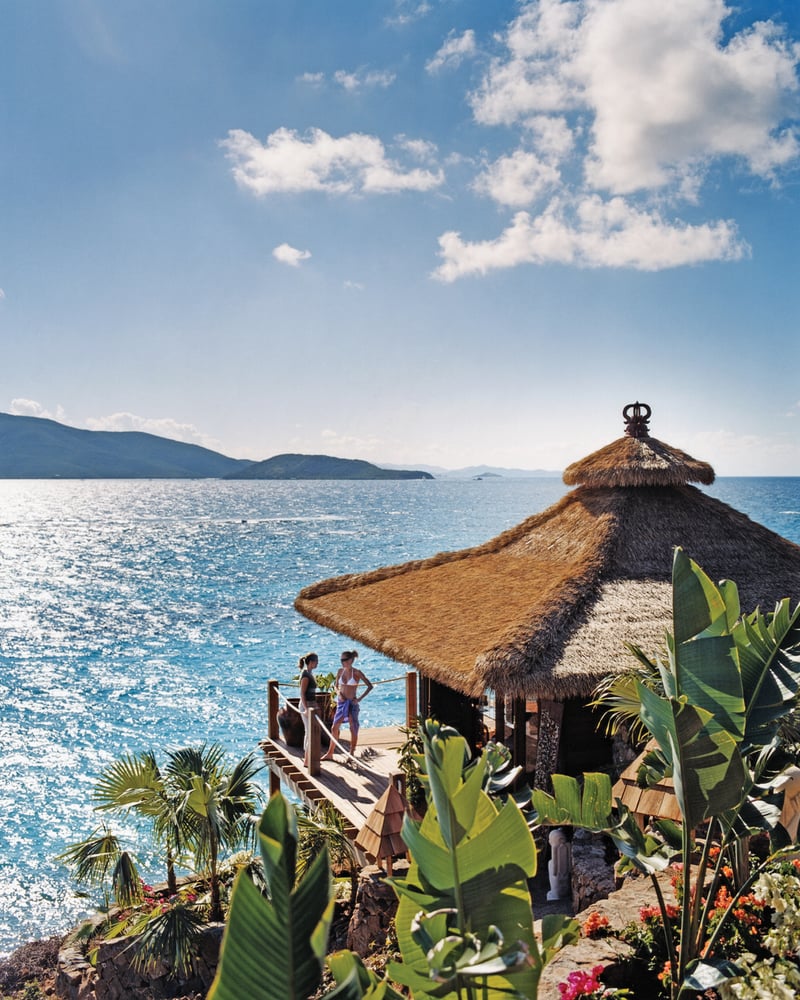 A villa with a thatched roof on the coast of Necker Island.