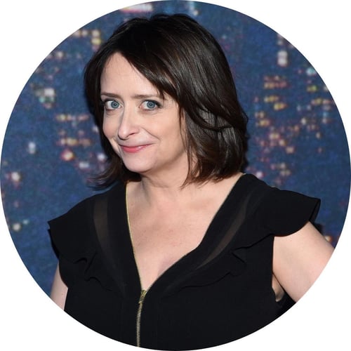 Rachel Dratch, wearing a black dress, smiles at the camera.