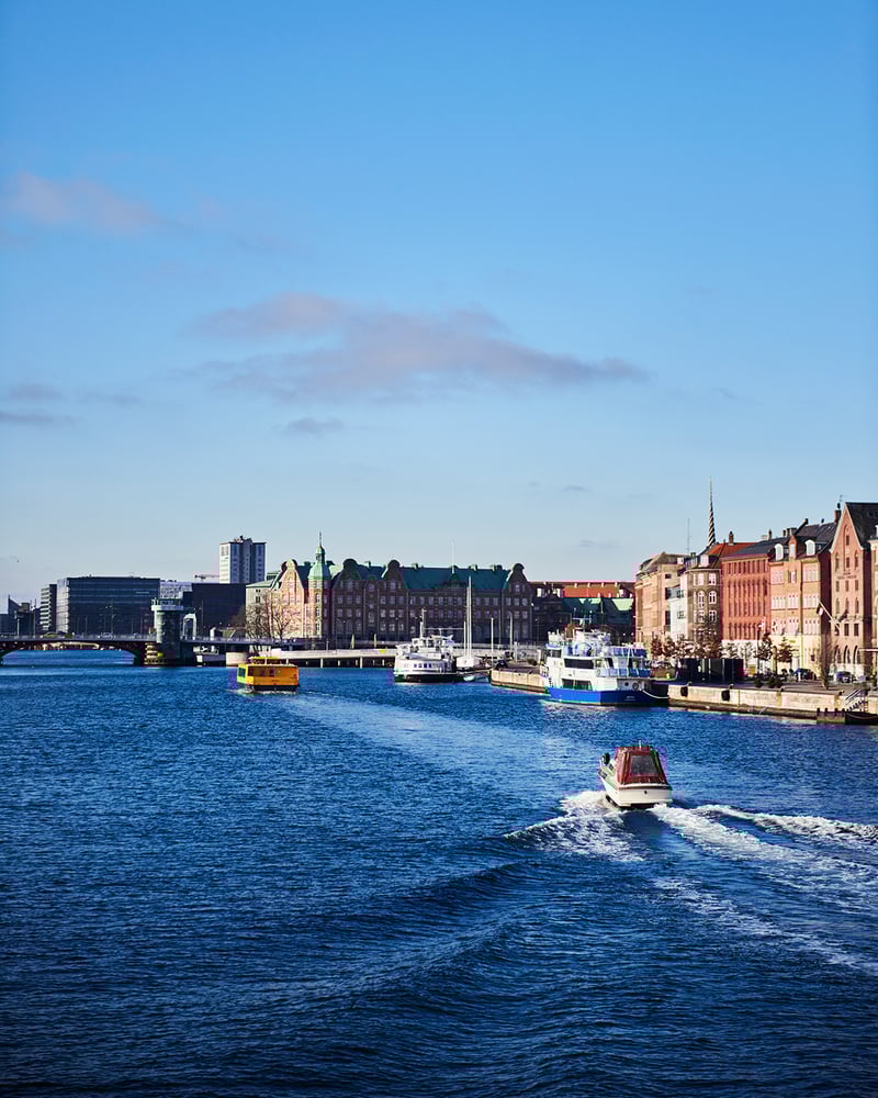 A water taxi travels through Copenhagen Harbor on a sunny day.