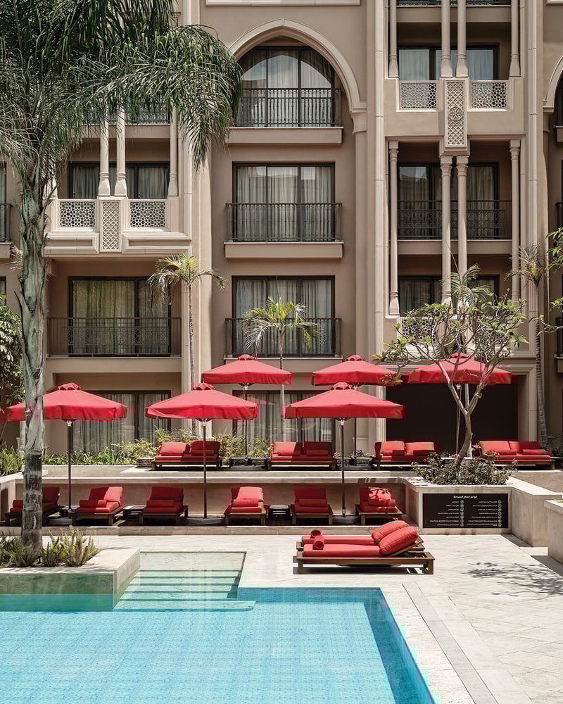 Red beach umbrellas and loungers surround the courtyard pool at Giza Palace.