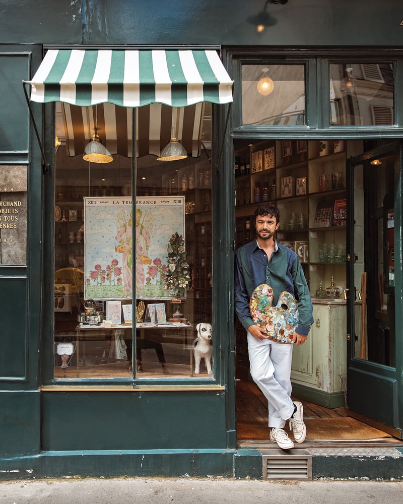Artist Marin Montagut holds a palette in the doorway of his shop.
