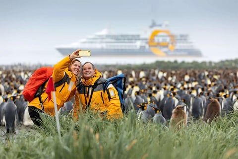A couple takes a selfie in front of hundreds of Emperor Penguins.