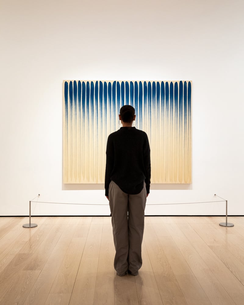 A woman stands facing an abstract painting at NYC’s Museum of Modern Art.