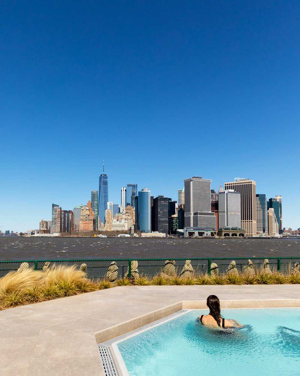 A woman in a pool overlooking the New York City skyline.