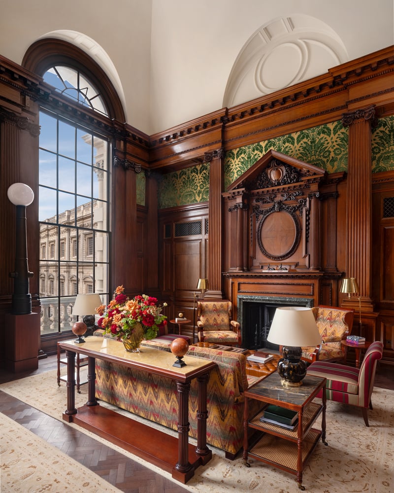 Red and orange furnishings in a wood-paneled room at Raffles London at the OWO.