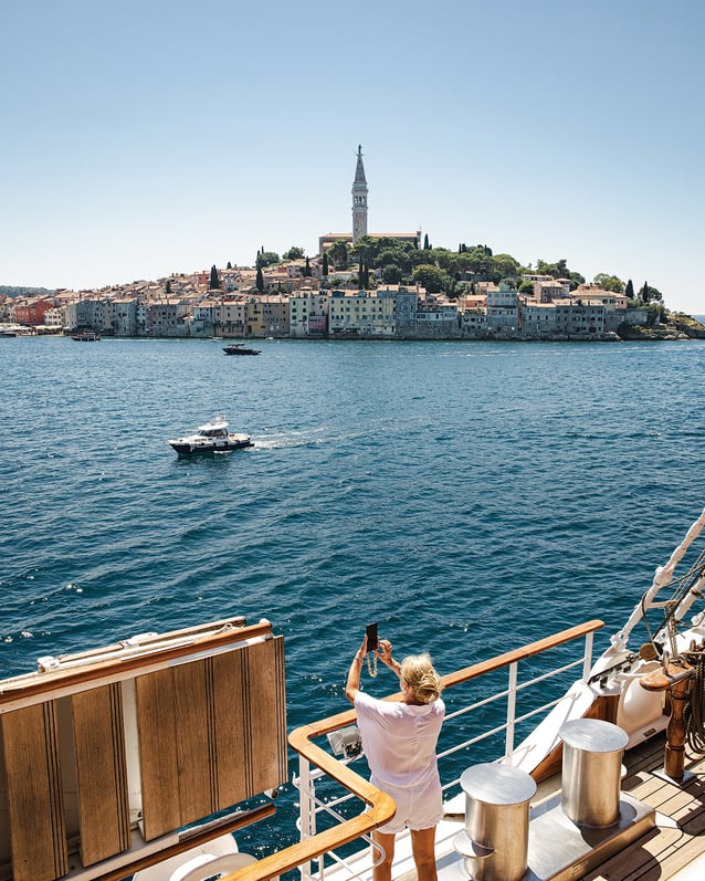 A woman photographs Old Town Rovinj in Croatia from the deck of the Sea Cloud Spirit.