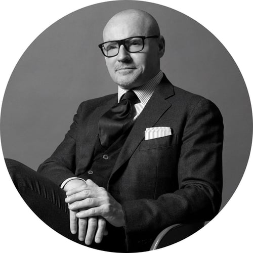 In a black-and-white photograph, Simone Giorgi, wearing a suit, grins and looks into the distance.