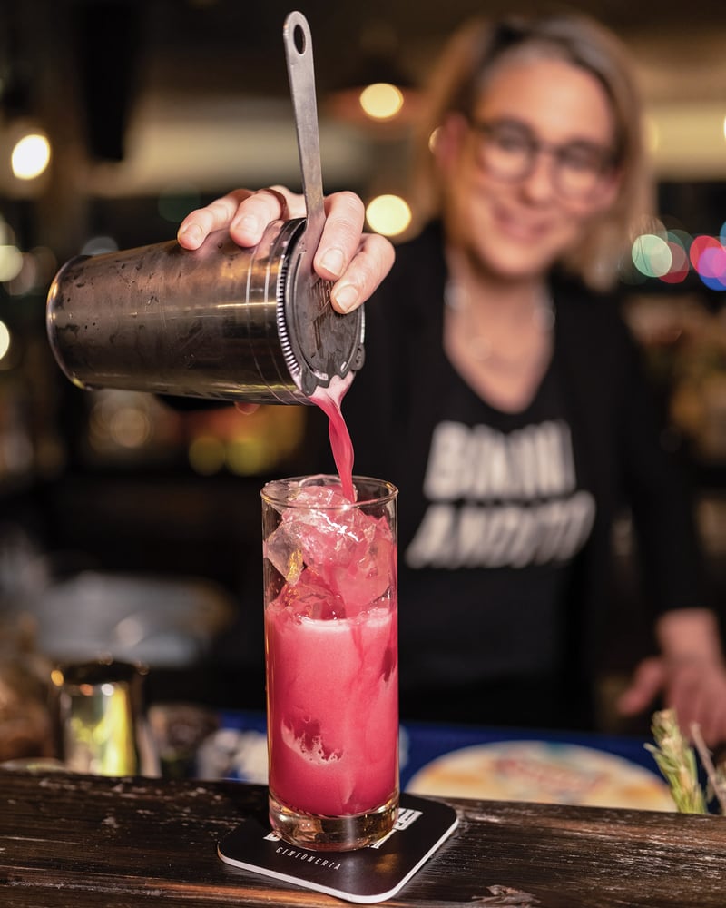 A server pours a bright-pink cocktail from a shaker into a glass at Jeremy Button Gintonería in Ushuaia.