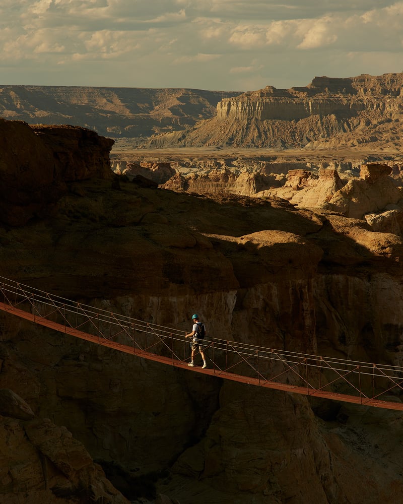 Climbers on Ajax Peak in Telluride, Colorado, with a green valley and a waterfall visible below them.