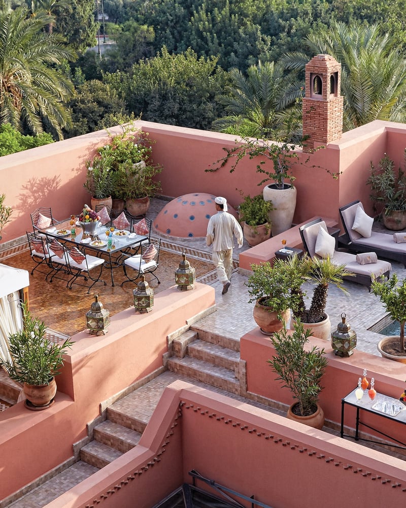 A man wearing a white outfit walks across a plant-bedecked terrace at Royal Mansour’s Grand Riad.