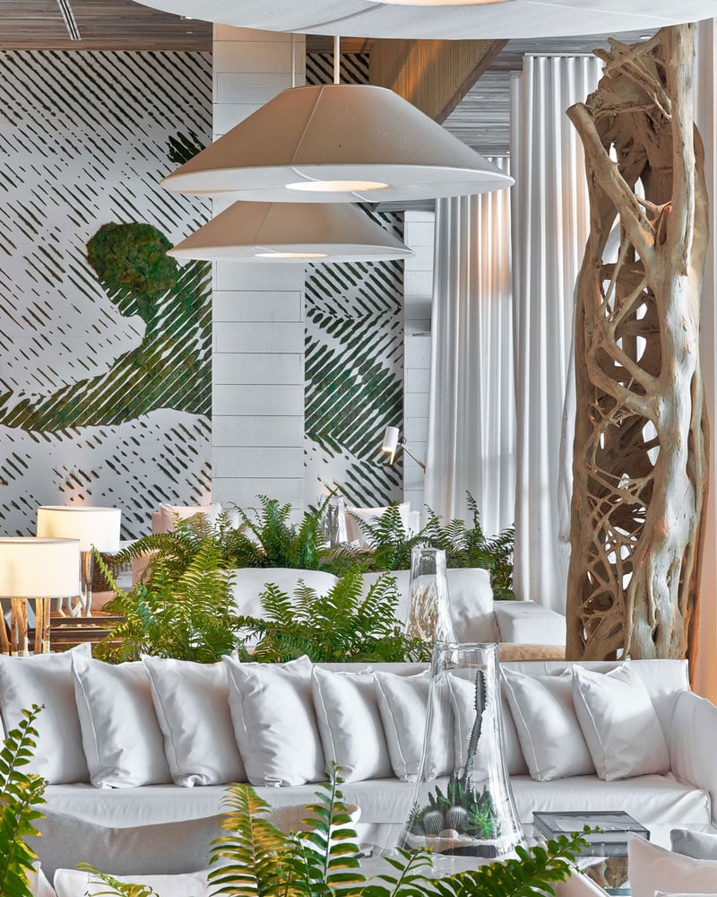 The lobby of 1 Hotel South Beach, which is filled with ferns and other plants along with white furniture.