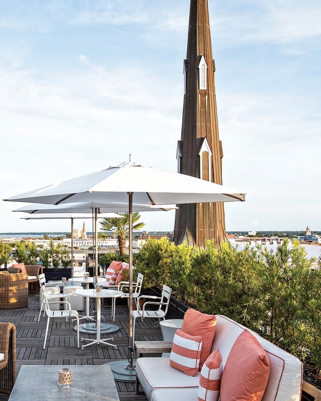 The rooftop bar at The Dewberry Charleston hotel, with pink and wicker accents, overlooks the city.