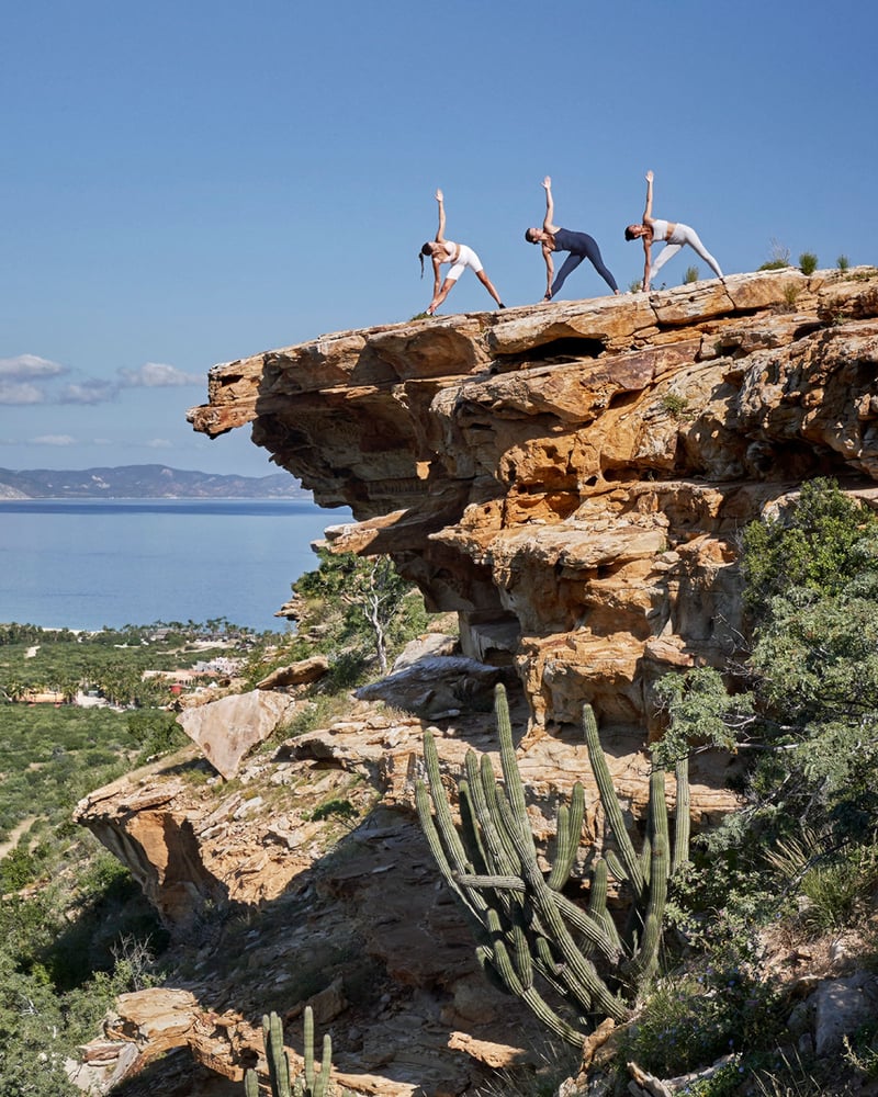 Three women practice yoga on a clifftop in Los Cabos, Mexico.