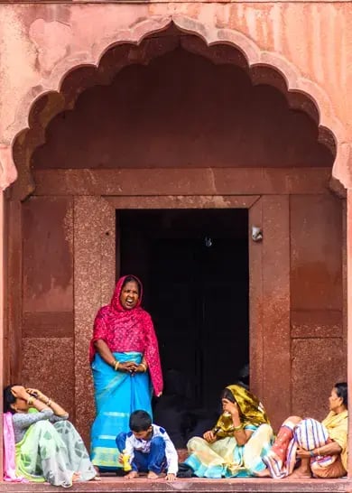 A woman in colorful traditional clothing laughs with a group of family or friends.